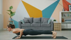 Woman doing a home plank exercise on a yoga mat, transitioning into downward dog stretch