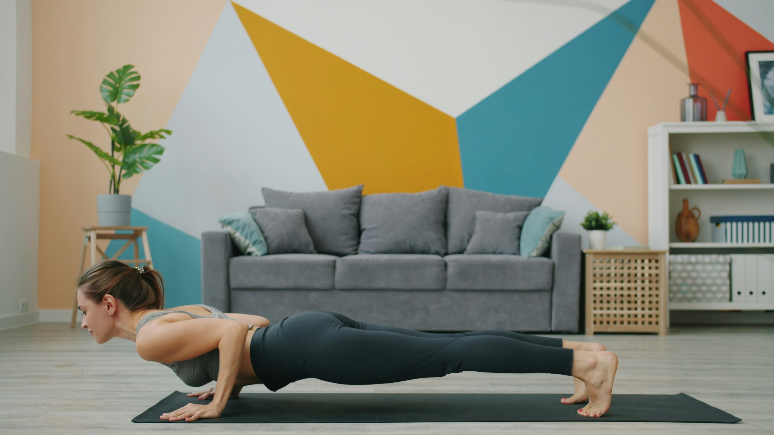 Woman doing a home plank exercise on a yoga mat, transitioning into downward dog stretch