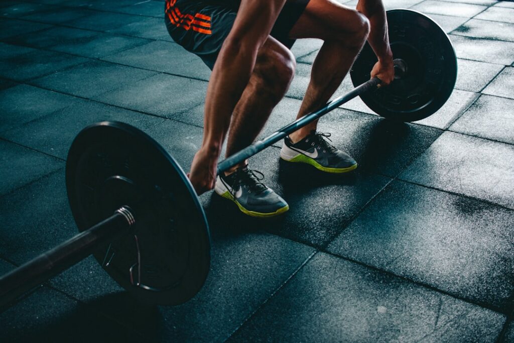 Person preparing to lift a barbell at the gym, representing a beginner fitness journey