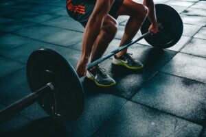 Person preparing to lift a barbell at the gym, representing a beginner fitness journey