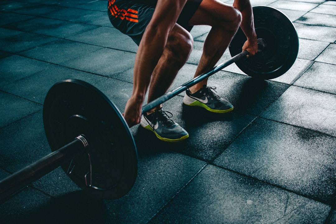 Person preparing to lift a barbell at the gym, representing a beginner fitness journey